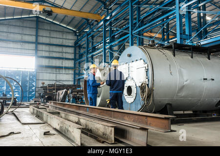 Lavoratore con esperienza di controllare la qualità del prodotto caldaie Foto Stock