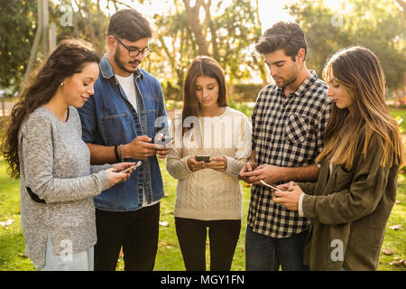 Gruppo di amici nel parco appendere fuori su reti sociali Foto Stock
