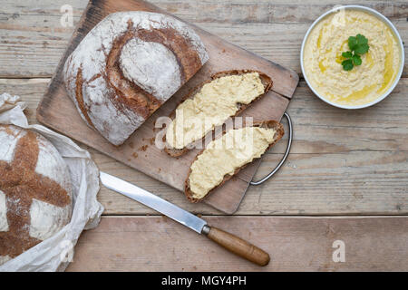 Pane e farina di farro con hummus fatto in casa su una tavola di pane. REGNO UNITO.