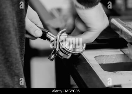 Close-up delle mani di un barista, professional corretto rinvenimento, la pressatura del macinato di caffè nell'azienda. Concetto di gustoso aroma coffee cultura, servic Foto Stock