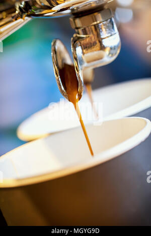 Close-up espresso fresco si riversa nella tazza monouso, Italiano macchina espresso. Cultura del caffè e professional per la preparazione di caffè, caffè per andare, servizio cateri Foto Stock