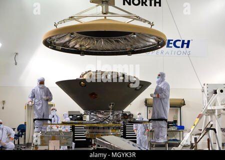 Nella struttura Astrotech tecnici ed ingegneri posizionare il heatshield su Marte della NASA Lander InSight prima dell'incapsulamento in suo payload carenatura presso la base aerea di Vandenberg Space Launch Complex 3 Marzo 29, 2018 in Lompoc, California. L'intuizione che sta per indagini sismiche, geodesia e trasporto di calore, sarà la prima missione a guardare in profondità sotto la superficie marziana ed è previsto per il decollo del 5 maggio 2018. Foto Stock