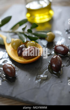 Olive e olio su una superficie di ardesia Foto Stock