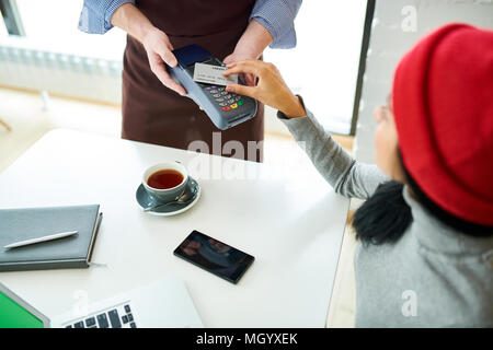 Giovane donna di pagare tramite NFC in Cafe Foto Stock