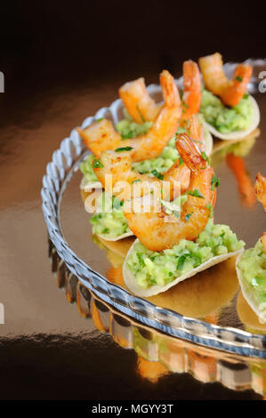 Uno snack leggero di patatine con riempimento di avocado e gamberi fritti aromatizzati con erbe aromatiche. Foto Stock