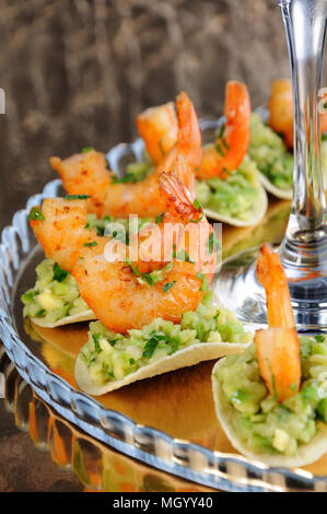 Uno snack leggero di patatine con riempimento di avocado e gamberi fritti aromatizzati con erbe aromatiche. Foto Stock