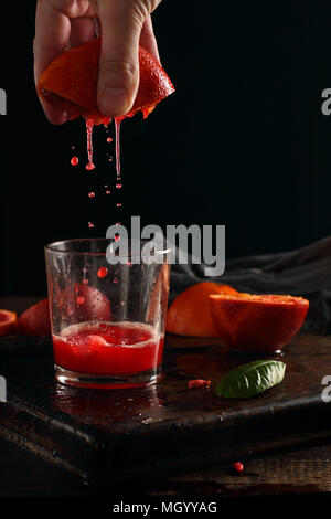 La spremitura di succo di arance sanguigne, fotografata con flash su sfondo nero Foto Stock