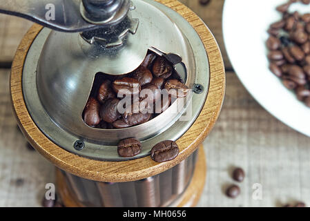 Close up i chicchi di caffè nel macinino sulla tavola di legno. Foto Stock