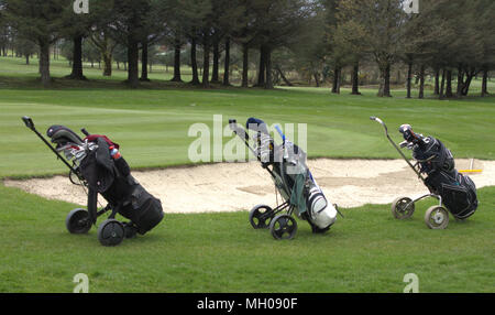 3 sacche da golf di sinistra in una linea accanto a un bunker di sabbia sul fairway di un campo da golf. Foto Stock