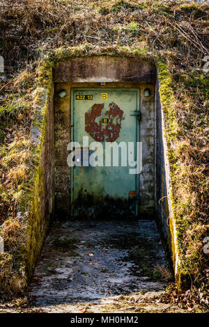 Rusty porta con un blocco su un bunker ricoperto di erba e muschio Foto Stock