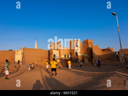 Arabia gli uomini a giocare a calcio nel mezzo di vecchie case, Najran provincia Najran, Arabia Saudita Foto Stock