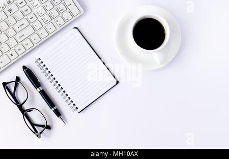 Scrivania da ufficio con la tabella vuota nella pagina del notebook con penna, computer e tazza di caffè. Vista superiore, piatto laici. Foto Stock