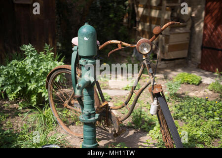 Un vecchio arrugginito bicicletta appoggiata ad una pompa per acqua, parte dell'Loisium esperienza del vino Museo al Loisium, Langenlois, Austria inferiore Foto Stock