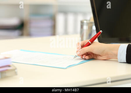 Close up ritratto di un dirigente di mano la firma di un modulo o un contratto su una scrivania in ufficio Foto Stock