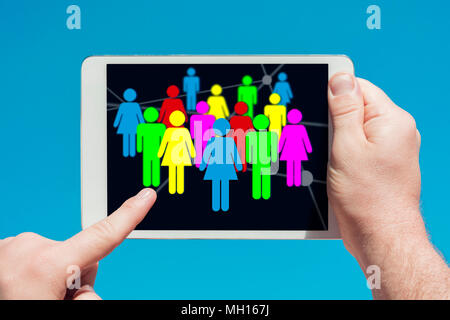 Uomo in possesso di un dispositivo tablet che mostra i social media e il concetto di comunicazioni, toccando lo schermo con un dito con il blu del cielo in background Foto Stock