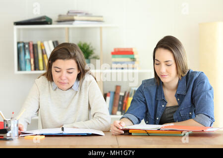 Due studenti di studiare insieme le note di lettura su un tavolo a casa Foto Stock