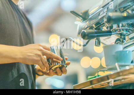 Vista da vicino le mani del barista professionale lavorando in una casa di caffè la preparazione di caffè espresso, sulla macchina per il caffè. Concetto di caffè, servizio, Foto Stock