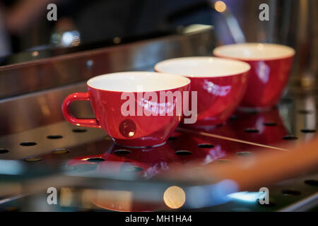 Tazze rosso sul supporto della macchina da caffè, bar. Vintage tono scuro, tempo di caffè, in background per l'uso. Cultura del caffè e professional caffè, s Foto Stock