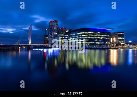 Vista notturna della oscillazione MediaCityUk ponte che conduce attraverso Media City e la BBC edifici per uffici visto dal lato sud della nave di Manchester Foto Stock