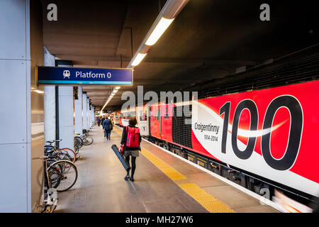 Passeggeri a piedi lungo la piattaforma 0 presso la stazione di Kings Cross per salire su un treno Foto Stock