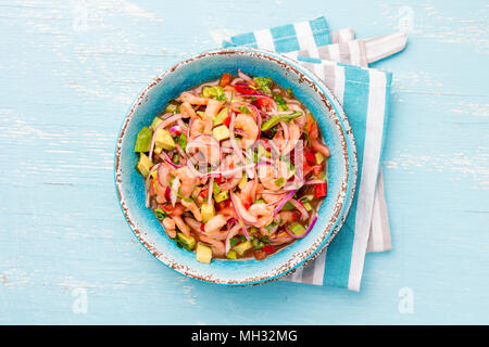 Cibo messicano. Gamberetti messicano ceviche sebiche con pomodori e avocado in blu ciotola di legno sfondo blu. Vista dall'alto. Foto Stock