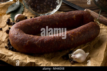 Il tedesco specialità salami hard indurito tutta la salsiccia con spezie sul tavolo di legno Foto Stock