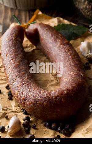 Il tedesco specialità salami hard indurito tutta la salsiccia con spezie sul tavolo di legno Foto Stock