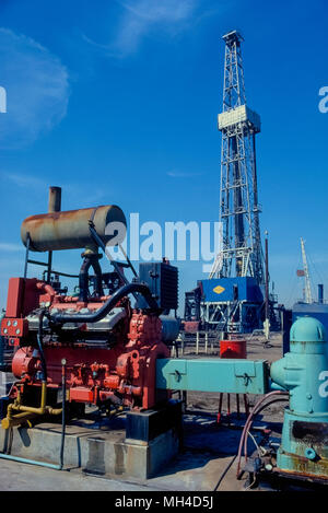 Un olio torreggianti derrick e apparecchiature di pompaggio per l'estrazione del petrolio dal sottosuolo è visto nel 1982 in Huntington Beach, California, Stati Uniti d'America, dove "oro nero" in primo luogo è stato colpito nel 1920 e iniziò un boom petrolifero in California del Sud. Negli ultimi anni molte delle pompe e l'olio-foratura derricks in questa città costiera sono stati sostituiti da abitazioni sviluppi. Fotografia storica. Foto Stock