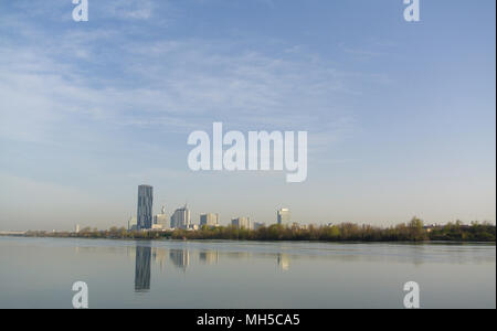 Fiume Danubio in mattina presto sotto la luce blu del cielo. L'altro lato hanno moderni grattacieli e riflessione di loro nel tranquillo fiume Foto Stock