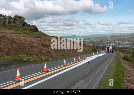 Ilkley Moor, West Yorkshire, Regno Unito. Il 30 aprile 2018. Artisti in appoggio le loro ginocchia dopo aver trascorso ore dipinto il Tour de Yorkshire il primo vertice finish sulla mucca e vitello strada pronti per il venerdì di gara. Che cosa sta andando essere? (Anamorfico land art) Rebecca Cole/Alamy Live News Foto Stock