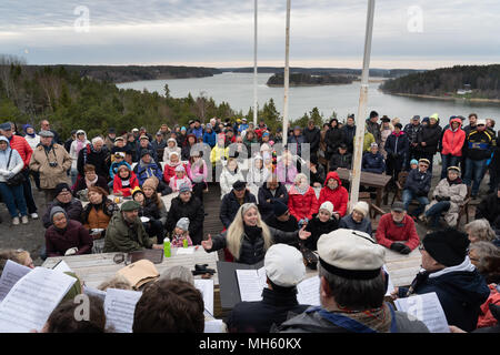 Arcipelago delle Isole Åland, Finlandia, 30 aprile 2018 persone indossano i loro cappelli di graduazione, cantare vecchie canzoni e costruire i falò in tutta la Finlandia e i paesi nordici per dire addio all'inverno e benvenuto in primavera. Nella foto: un coro locale condotta dal famoso musicista Åland Johanna Grussner cantare vecchie canzoni nordica sulla roccia di Uffe På Berget sulle isole Åland. Immagine: Rob Watkins/Alamy News Foto Stock