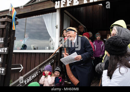 Arcipelago delle Isole Åland, Finlandia, 30 aprile 2018 persone indossano i loro cappelli di graduazione, cantare vecchie canzoni e costruire i falò in tutta la Finlandia e i paesi nordici per dire addio all'inverno e benvenuto in primavera. Nella foto: Le corna vengono soffiati a usher fuori stagione invernale e usher in primavera sulla roccia di Uffe På Berget sulle isole Åland. Immagine: Rob Watkins/Alamy News Foto Stock