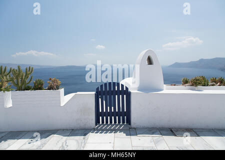 Bianco parete lavata e blue gate che si affacciano sull'oceano blu di Santorini Foto Stock