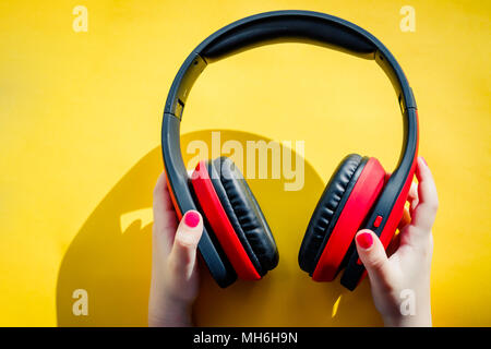 Cuffie senza fili in mano femmina isolati su uno sfondo giallo con area di pubblicità come la tecnologia digitale o il concetto di musica.bluetooth e percorso di clipping.ascolto un concetto di musica. Foto Stock