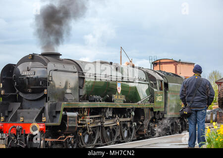 Vista posteriore dell'uomo guarda vintage UK locomotiva a vapore 34027 Valle Taw assunzione di acqua al fianco di piattaforma, Kidderminster Severn Valley Railway Station. Foto Stock