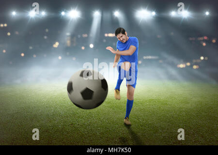 Giovani asiatici giocatore di calcio ripresa la palla sul campo Foto Stock