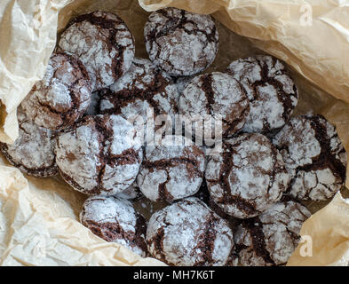 Chocolate crinkle cookies con polvere di glassa di zucchero. Incrinato biscotti al cioccolato su sfondo della carta. close up. vista superiore Foto Stock