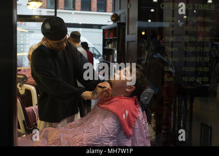 L'uomo avente una rasatura in un barbiere presso la Old Spitalfields Market East London Foto Stock