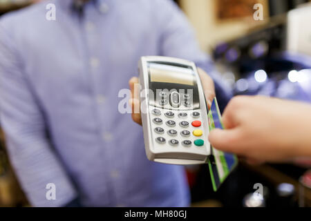 Immagine del venditore con terminale in mani e acquirente con la carta di credito. Foto Stock