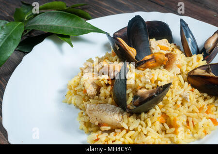 Riso con carne e verdure e cozze su un vecchio tavolo di close-up. Foto Stock