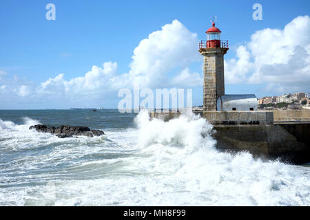 Tempesta onde di oltre faro e cielo blu a Porto, Portogallo Foto Stock