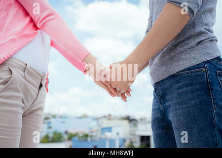 Giovane bella donna e uomo asiatico ridere contro il cielo blu scuro con le nuvole Foto Stock