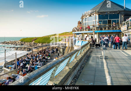 I turisti in vacanza al Fistral Beach Bar godendosi il sole serale nella Cornovaglia di Newquay. Foto Stock