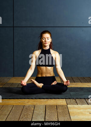 Foto di una giovane e bella donna fare la posizione del loto di esercizi yoga. Foto Stock