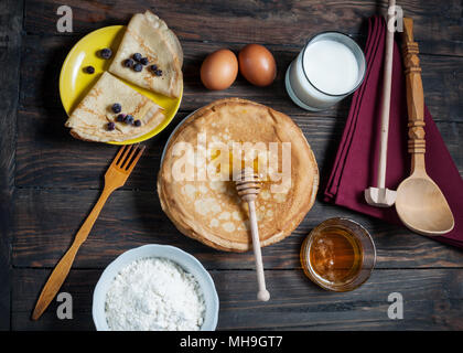 Pila di crepes e gli ingredienti per cucinare su una tavola di legno. Foto Stock