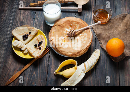 Frittelle con miele e gli ingredienti su sfondo di legno. Foto Stock