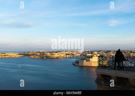 I maltesi e i visitatori si riuniscono ai giardini di Tivoli al tramonto per ammirare il panorama e trovare un momento tranquillo. Valletta, Malta Foto Stock