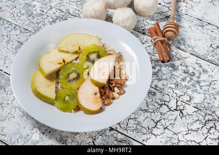 Farina di avena con mele, pere, noci e kiwi in una ciotola bianco. Vista dall'alto. Foto Stock