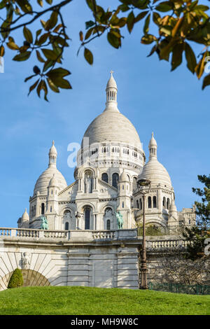 La basilica del Sacro Cuore di Parigi in cima alla collina di Montmartre visto da Louise Michel park con fogliame in primo piano. Foto Stock