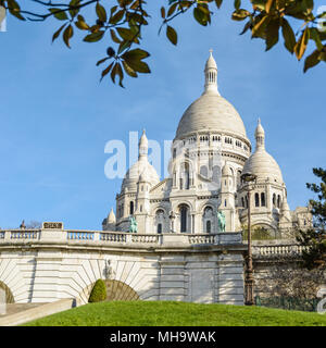 La basilica del Sacro Cuore di Parigi in cima alla collina di Montmartre visto da Louise Michel park con fogliame in primo piano. Foto Stock